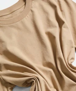 Close-up image of a beige unisex oversized t-shirt showing the fabric texture and color details.