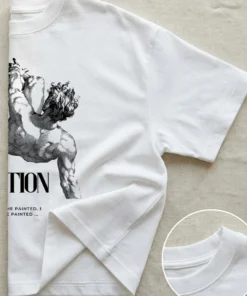 Half-folded flatlay of an oversized white T-shirt showing the inspirational artist quote design.