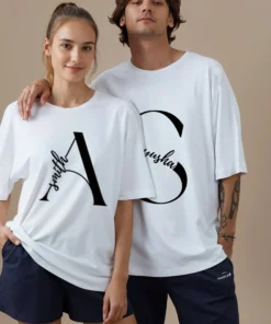 Couple wearing personalized white oversized matching t-shirts with custom names printed on premium cotton fabric for pre-wedding photoshoots and anniversary gifting.